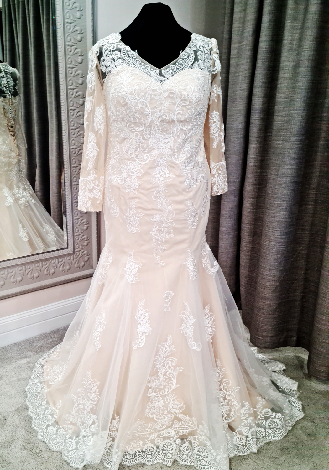 Ivory trumpet style wedding dress with lace applique, long sleeves, sweetheart neckline, corset back, and lace edged train